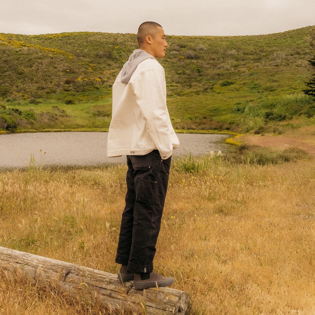 Person standing in a field wearing Ballard Boots in Charcoal, side profile.