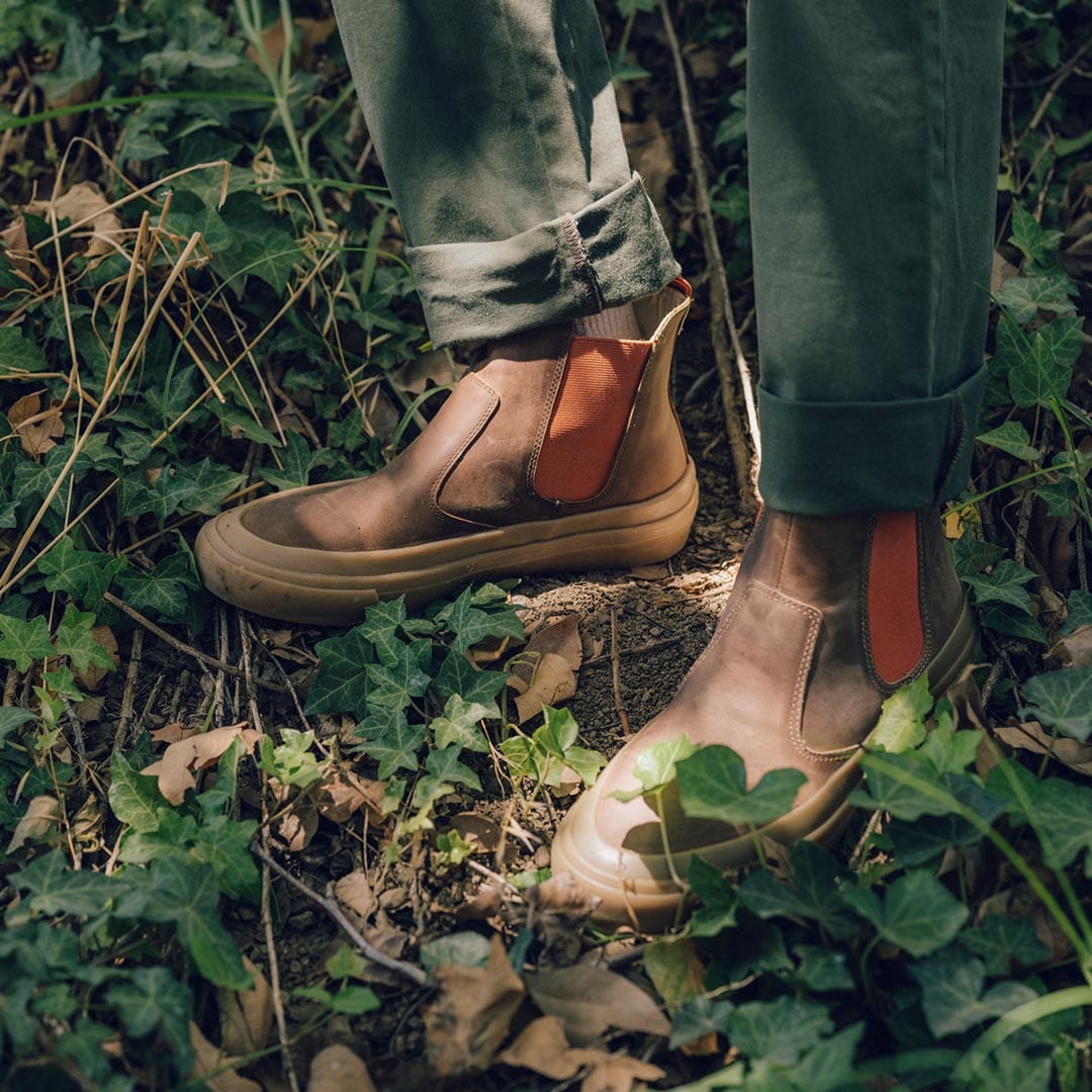 Beyond & Back Boots in Elmwood from the back, showcasing the heel tab and elastic detail amid a backdrop of green ivy