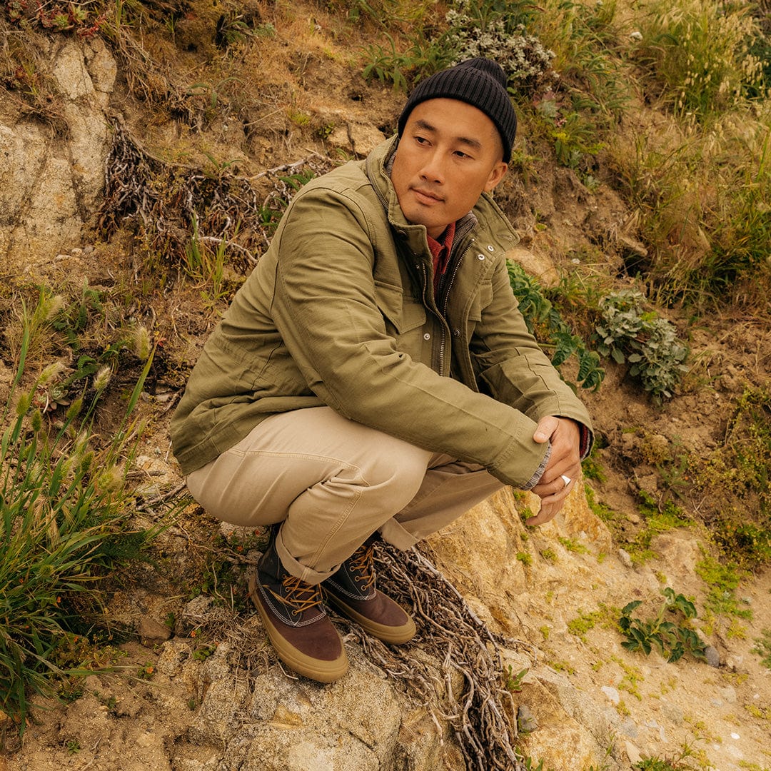 Casual pose with a man sitting in grass wearing Hickory/Charcoal Cascade Range Boots, ideal for outdoor adventures.