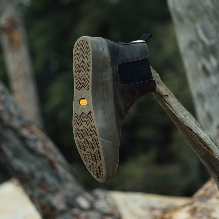 Men's Beyond & Back Boot in Bark leather, outsole view showing the Vibram sole, resting on a log