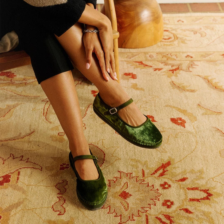 Women's Carlyle Mary Jane in Dark Moss fabric, worn by a seated person with hands on knees on a patterned rug