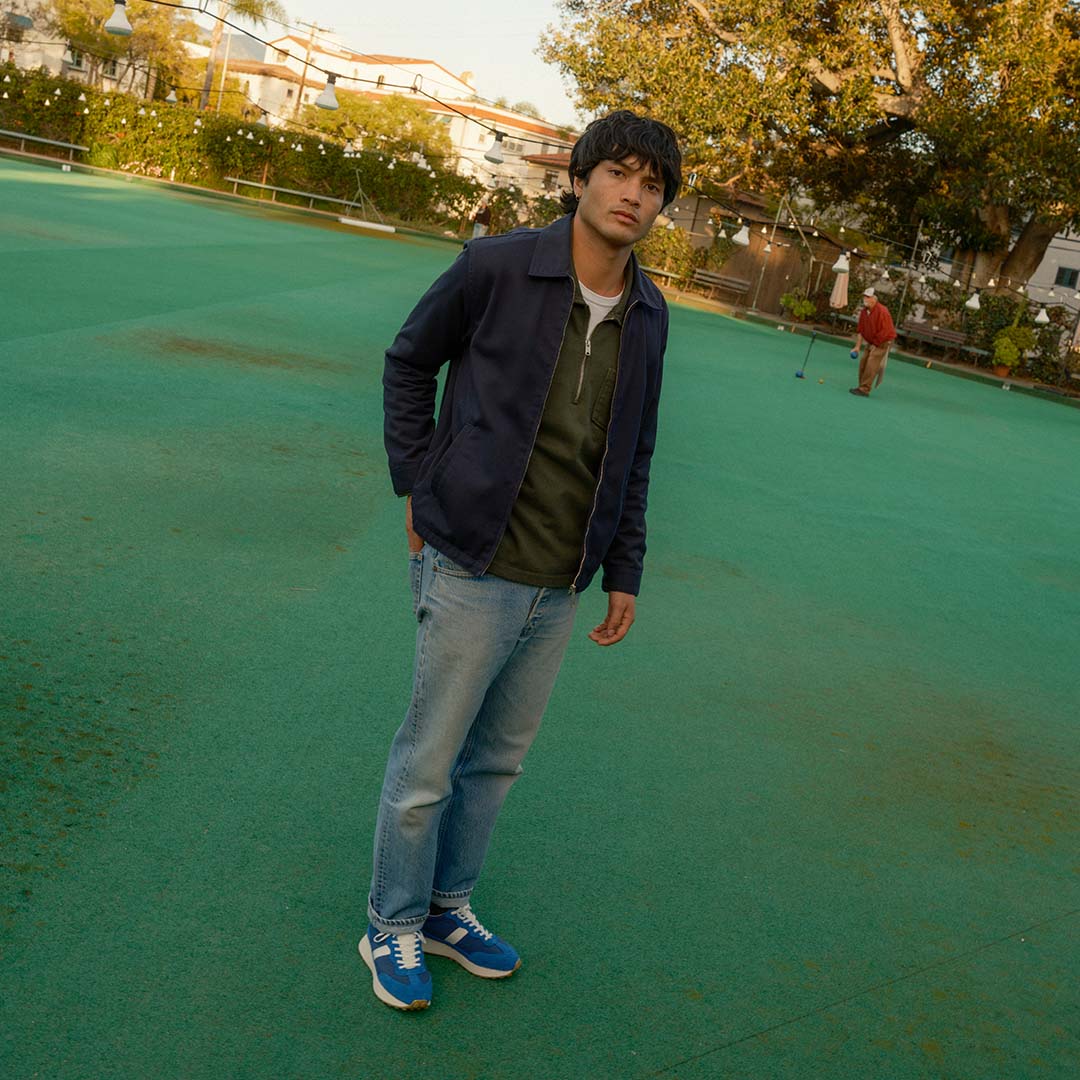 Person standing on a putting green wearing the Acorn Trainer in Varsity Blue.
