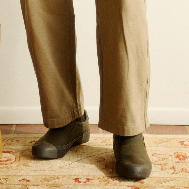 Men's Hawthorne Slip On in Black Olive leather, worn with khaki pants on a patterned rug