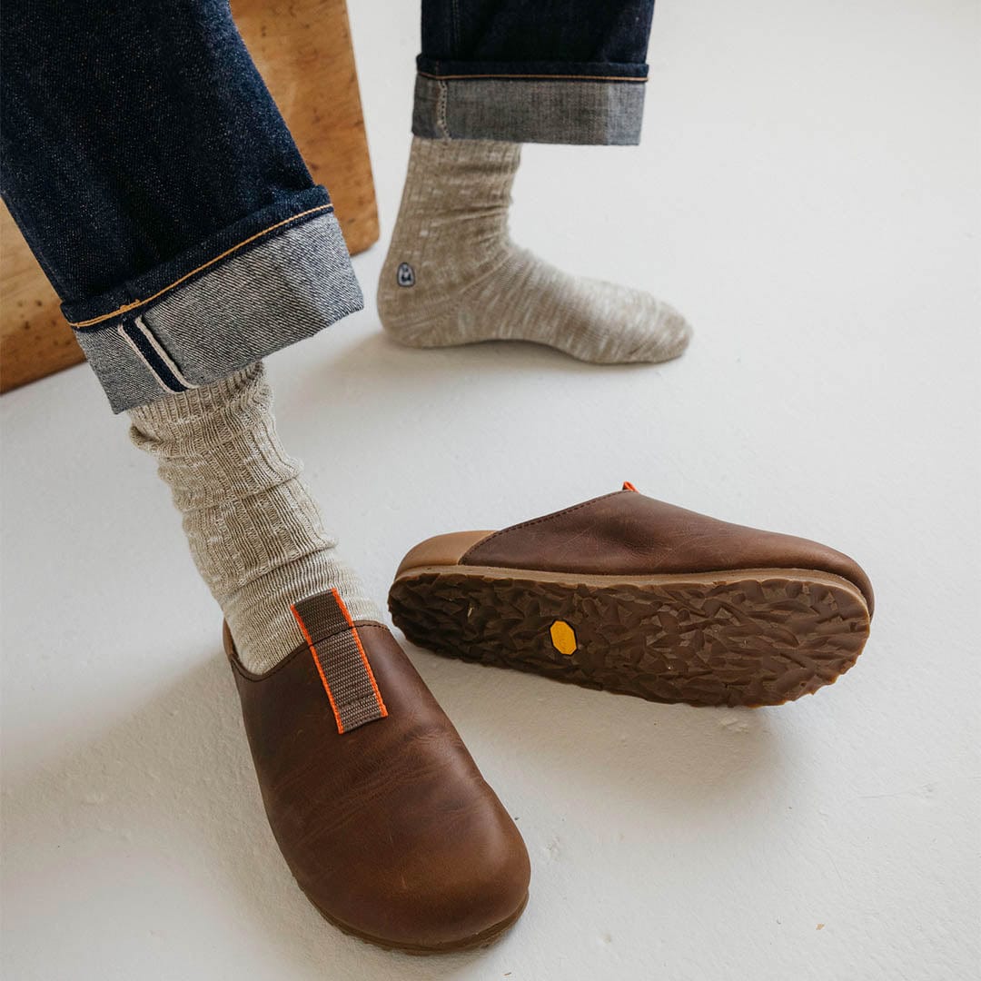 Men's Tiburon Trekker sandal in Elmwood leather, worn with rolled jeans, one shoe showing the outsole