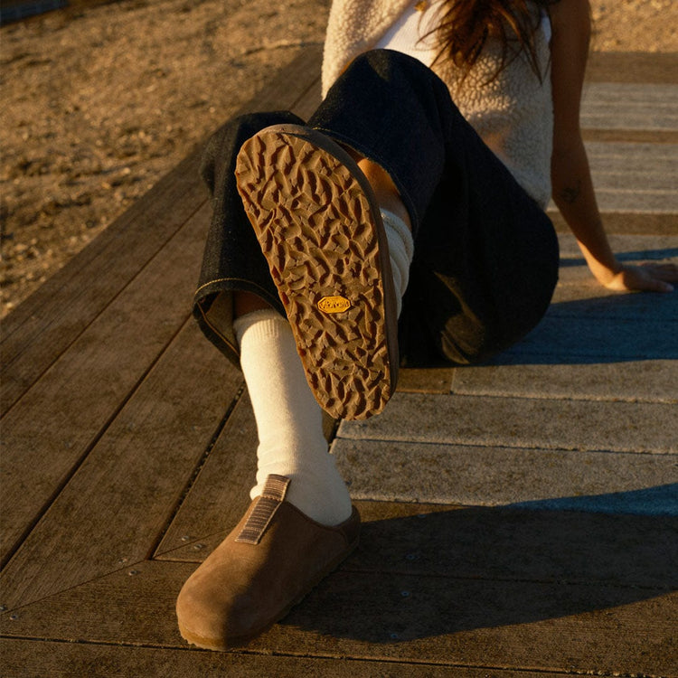 Women's Tiburon Trekker sandal in Fossil leather, worn on a wooden deck, sole visible
