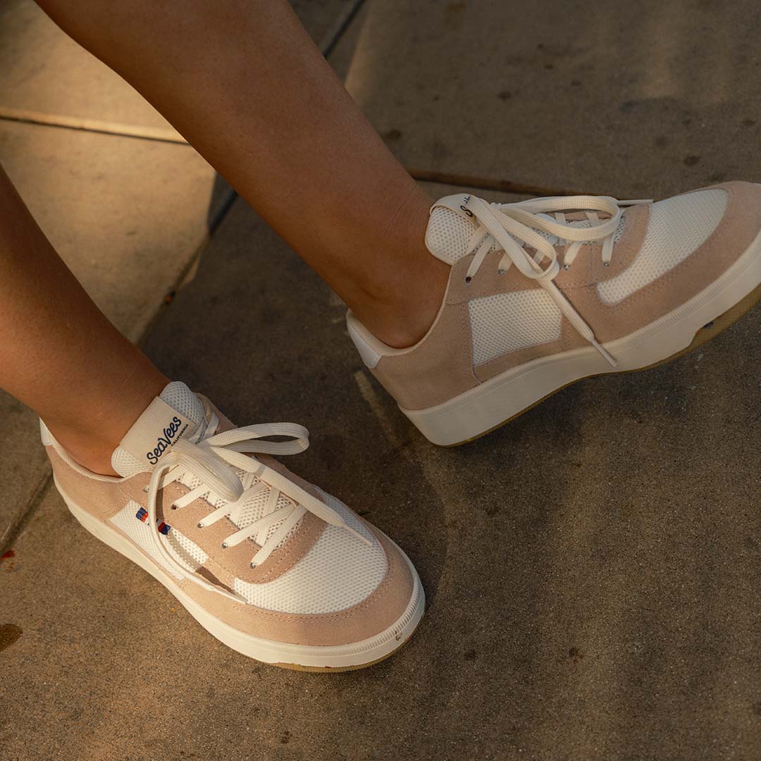 Close-up view of someone's feet wearing the Cardinal Sneaker in Pink Sand