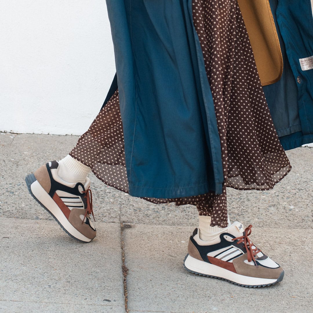 Women's Causeway Trainer sneaker in All Spice mesh and leather, worn with white socks and a long skirt on pavement