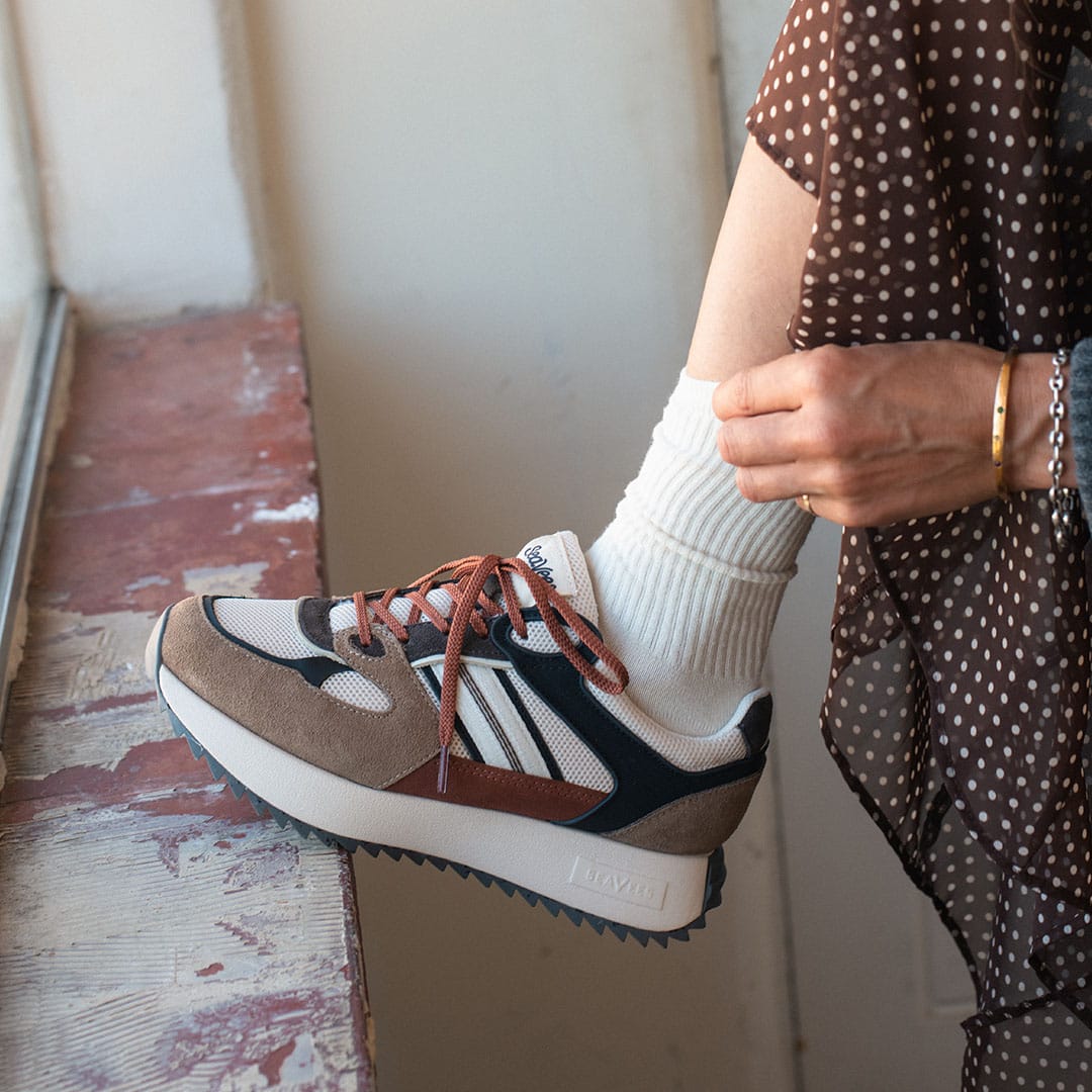 Women's Causeway Trainer sneaker in All Spice mesh and leather, worn with white socks, laces being tied, brown polka dot