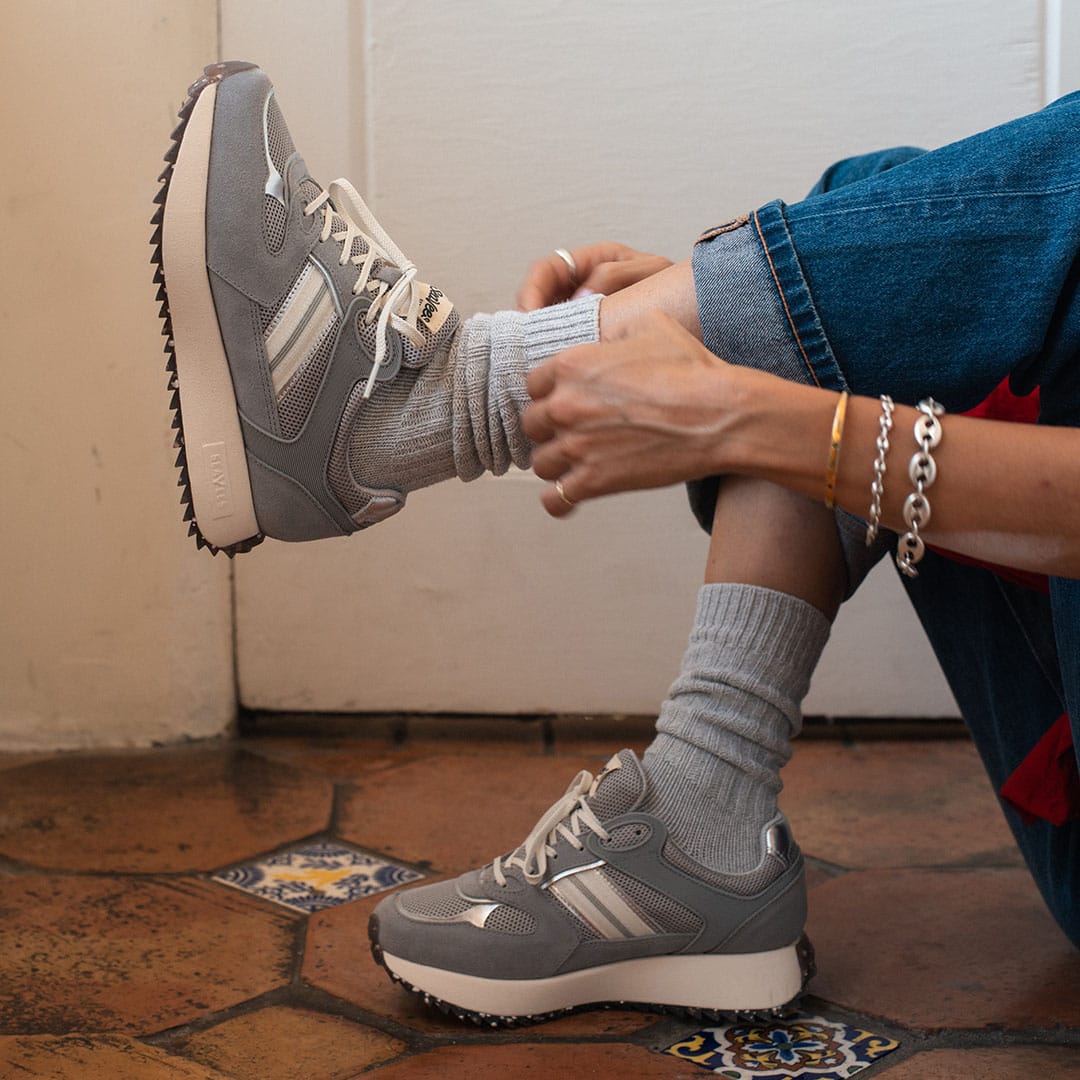 Women's Causeway Trainer sneaker in Moon Rock mesh and leather, worn with gray socks and rolled jeans on terracotta tile