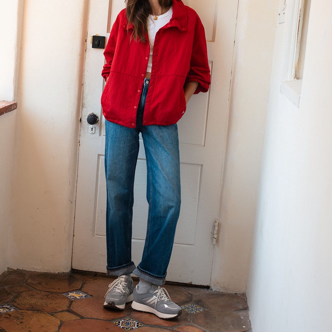 Women's Causeway Trainer sneaker in Moon Rock mesh and leather, worn by a person standing in a red jacket and jeans