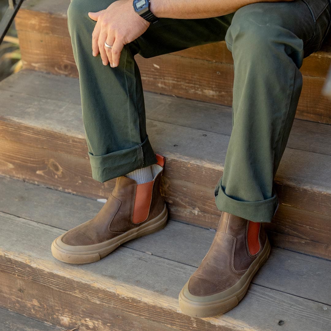 Casual pose with Beyond & Back Boots in Elmwood, person sitting on wooden stairs, highlighting the boot's side design and sole