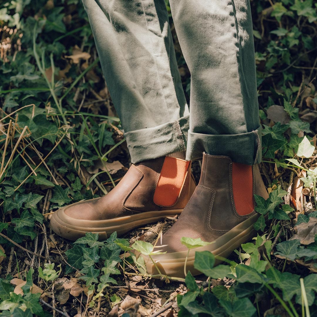 Natural setting with Beyond & Back Boots in Elmwood, person standing among foliage, emphasizing the boot's profile and design