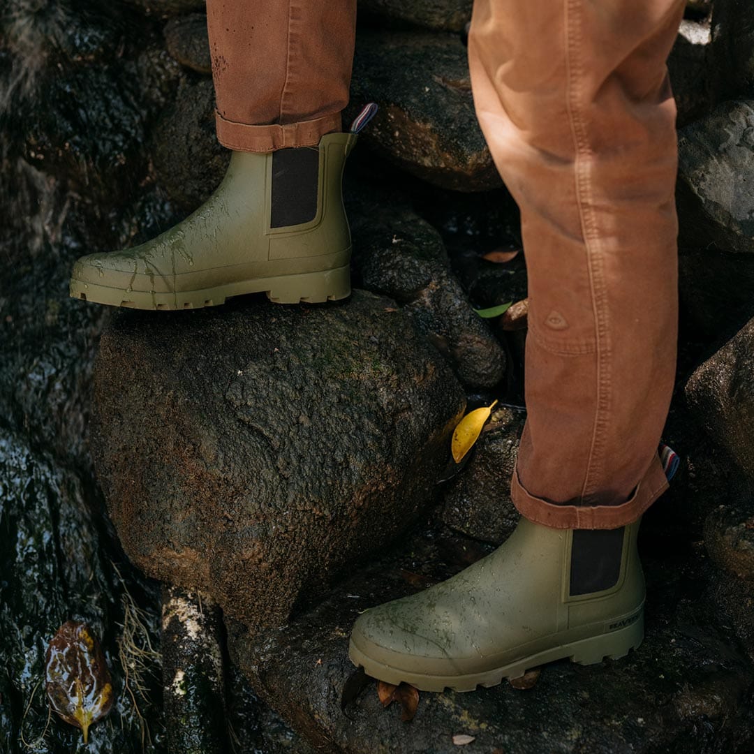 Person walking on rocky terrain in Bolinas Off Shore Boots in Military Olive.